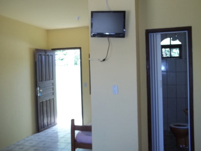 Quarto casal, com TV, ventilador de teto e banheiro privativo.