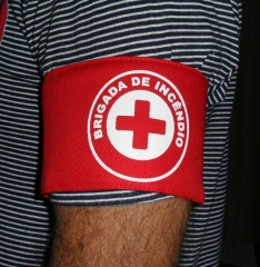 Braadeira brigada de incndio modelo cruz, confeccionada em brim 100% algodo, com fechamento em velcro e emblema estampado em branco.