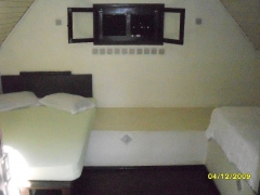 Cabana com cama de casal, solteiro, tv, ventilador de teto e banheiro compartido